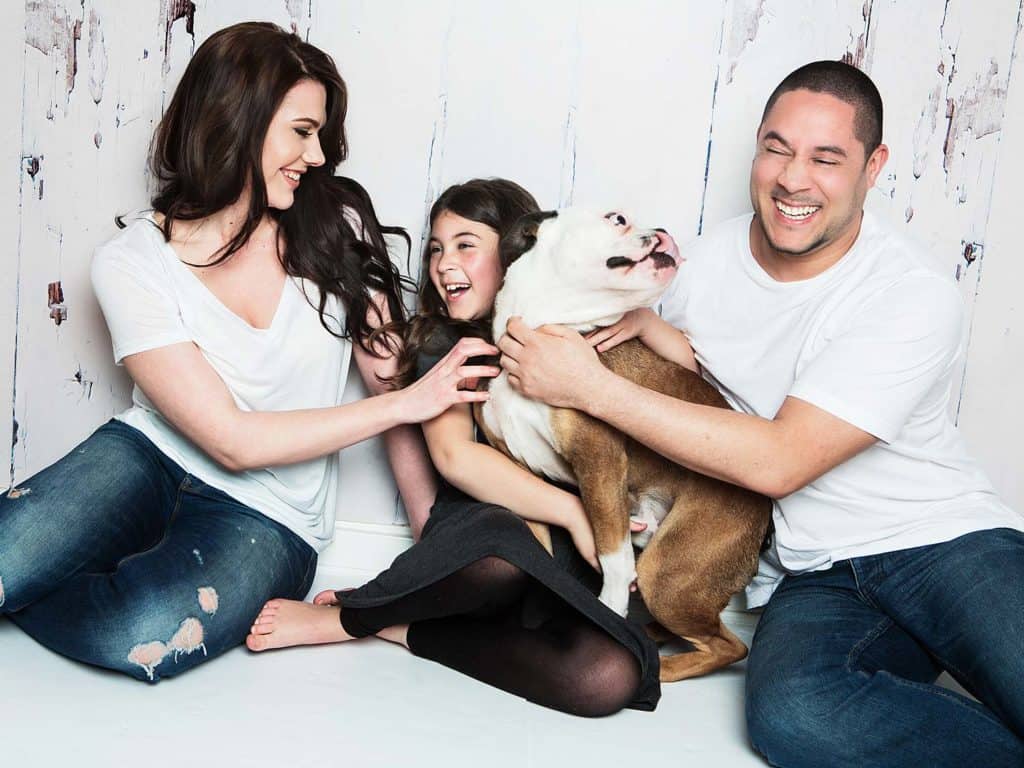 A family of three, poses in front of a family photographer in Cambridge.