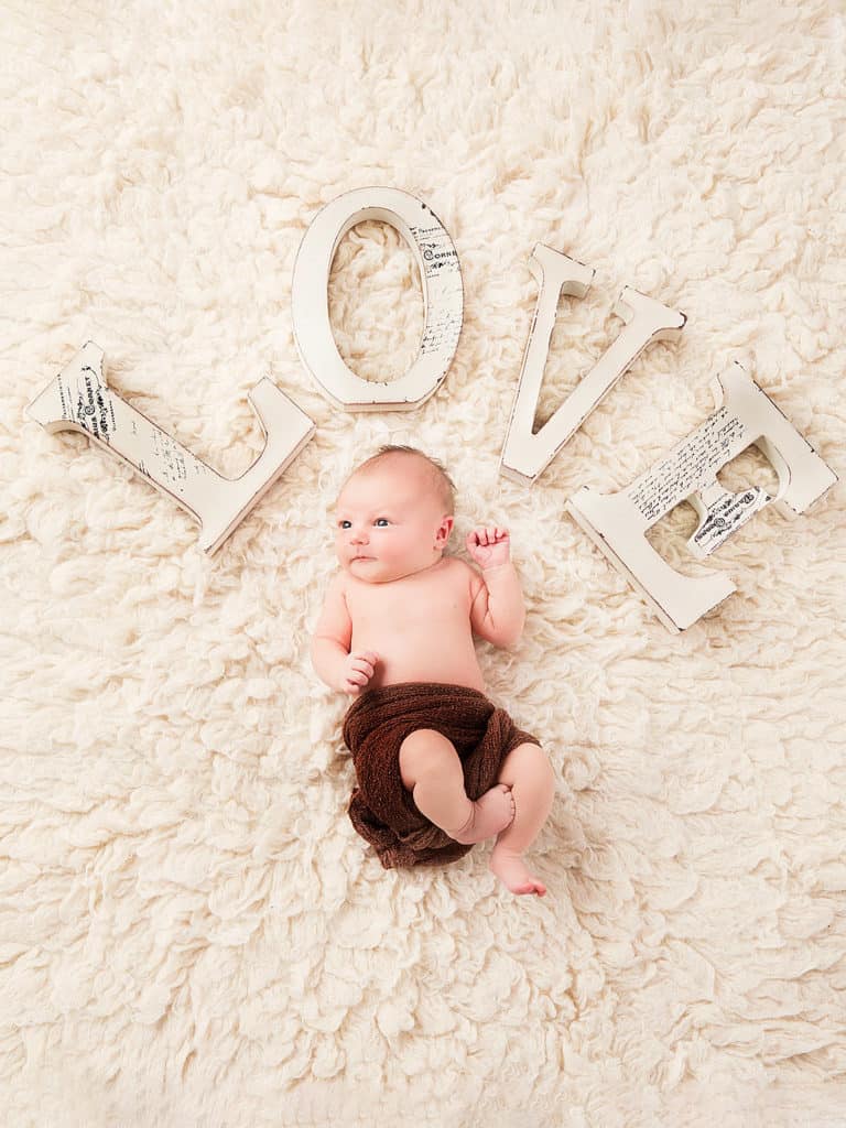 cute newborn baby is looking at professional photographer in Cambridge